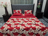 Red and beige floral bedspread on a bed with matching pillows, set against a gray upholstered headboard.